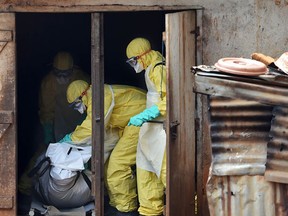 (FILES) - A photo taken on November 12, 2014 shows health workers from Sierra Leone's Red Cross Society Burial Team 7 preparing to carry a corpse out of a house in Freetown. The UN health agency said on November 7, 2015 Ebola-ravaged Sierra Leone had beaten an 18-month outbreak that killed almost 4,000 of its people and plunged the economy into severe recession.