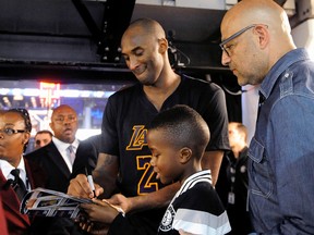 Los Angeles Lakers forward Kobe Bryant signs an autograph for a young fan as he walks off the court after the Lakers defeated the Brooklyn Nets 104-98 in an NBA basketball game Friday, Nov. 6, 2015, in New York. (AP Photo/Kathy Kmonicek)