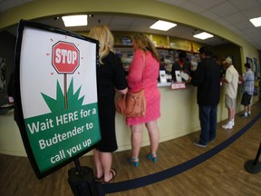 In this photograph taken with a fisheye lens Saturday, April 25, 2015, marijuana buyers make their purchases at the counter in northeast Denver, Colorado. (AP Photo/David Zalubowski)