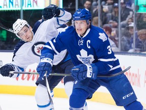 Winnipeg Jets' Adam Lowry, left, and Toronto Maple Leafs' Dion Phaneuf fight for position during first period NHL hockey action, in Toronto, on Wednesday, Nov. 4, 2015. THE CANADIAN PRESS/Darren Calabrese