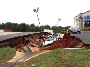 This photo shows vehicles after a cave-in of a parking lot in Meridian, Miss., Sunday, Nov. 8, 2015. Experts are to begin work Monday seeking to determine the cause of the Saturday collapse, authorities said. (Michael Stewart/The Meridian Star via AP)