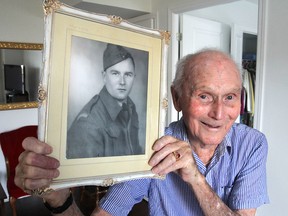Gene McGlynn, now 98 and living in Kingston, Ont. on Thursday, Oct. 22, 2015, holds up a photo of himself as a soldier during the Second World War, when he guarded Axis prisoners at at prison camp in Quebec. (Michael Lea/The Whig-Standard)