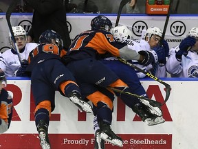 Daniel Muzito-Bagenda of the Mississauga Steelheads is hit by Cullen Mercer and Bryce Yetman of the Flint Firebirds during OHL game action at the Hershey Centre in Mississauga on Oct. 4, 2015. (Graig Abel/Getty Images/AFP)
