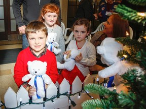 Emmett, left, Maeve and Aida Phillips all put a fundraising teddy bear on the holiday tree at Kingston General Hospital after their mother, Tabitha Lollar, spoke about her family's experience when young Aida was admitted to the Pediatric Unit and the care she received, during the launch of the Kingston General Hospital Auxiliary's annual Teddy Bear campaign. Julia McKay/The Whig-Standard