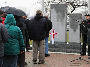 People gathered for the Aamjiwnaang First Nation's annual Remembrance Day Tuesday wait to pin poppies at the foot of the cenotaph. About 70 people attended the ceremony. (Tyler Kula, The Observer)