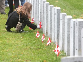 Schoolchildren place flags on the military headstones in Cataraqui Cemetery in Kingston, Ont. on Tuesday, Nov. 10, 2015 prior to a pre-Remembrance Day ceremony in the cemetery's military section. Michael Lea/The Whig-Standard/Postmedia Network