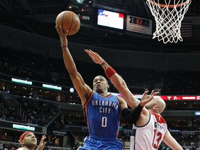 Oklahoma City Thunder guard Russell Westbrook (0) shoots between Washington Wizards guard Jared Dudley (1) and center Marcin Gortat (13) during the first half of an NBA basketball game, Tuesday, Nov. 10, 2015, in Washington. The Thunder won 125-101. (AP Photo/Alex Brandon)