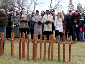 People walk up to place wooden crosses on the grass next to the Ainsworth Dyer Bridge that spans the North Saskatchewan River between Rundle Park and Capilano Park in Edmonton, Alta., on Wednesday Nov 11, 2015. The  158 crosses have the names of every soldier killed in Afghanistan during the Canadian mission there. Tom Braid/Edmonton Sun/Postmedia Network
