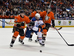 Oilers left wing Benoit Pouliot (67) and Anaheim Ducks players Josh Manson (42) and Shawn Horcoff (22) and Chris Stewart (29) reach for the puck Wednesday at Honda Center. (USA TODAY SPORTS)