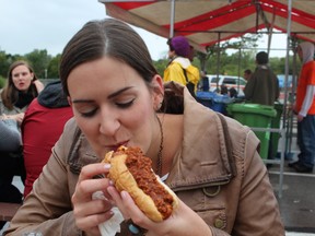 St. Catharines resident Ashley Vanleeuwen bites into a chili dog served by the Blue Star at the Niagara Food Festival. Allan Benner/Postmedia Network