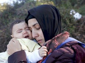 A Syrian refugee hugs her crying baby after arriving on a raft on the Greek island of Lesbos, October 27, 2015. According to United Nations over half a million refugees and migrants have arrived by sea in Greece this year and the rate of arrivals is rising, in a rush to beat the onset of freezing winter. Several churches and faith groups in Sarnia are working to sponsor refugee families. (REUTERS/Giorgos Moutafis      TPX IMAGES OF THE DAY)