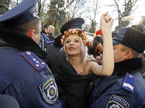 Policemen detain an activist in front of the parliament building in Kiev, Ukraine, Thursday, Nov. 12, 2015. The activists demanded Ukrainian lawmakers approve a bill that bans discrimination of gays.  (AP/Volodymyr Donsov)