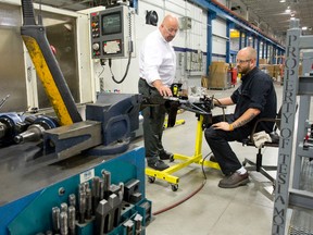 Technical sales representative Don Wilson, left, consults with operator Shawn Ridley as they make parts to be shipped to electric sports car maker Tesla at Attica Manufacturing in London. (CRAIG GLOVER, Free Press file photo)