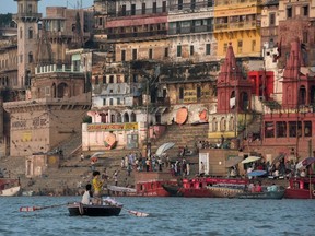 A tourist on a boat, lower left, takes a photograph of the waterfront on the banks of the River Ganges at Varanasi, India, on September 18, 2015. (AFP PHOTO / ALEX OGLE)