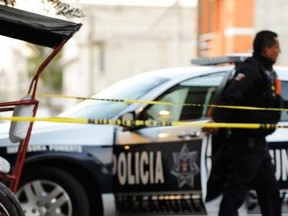 In this February 16, 2014, a police officer walks behind a yellow police line at a crime scene in Nezahualcoyotl, Mexico. (REUTERS/Alejandro Dias)