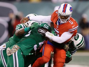 Bills quarterback Tyrod Taylor (right) is hit by several Jets players during first half NFL action in East Rutherford, N.J., on Thursday, Nov. 12, 2015. (Seth Wenig/AP Photo)