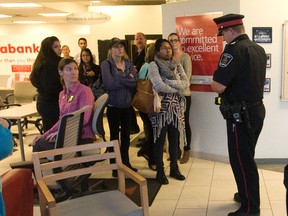 A policeman interviews people inside the Scotiabank at 639 Southdale Rd. after it was robbed  in London on Thursday. Derek Ruttan/The London Free Press/Postmedia Network