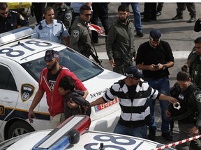 Israeli security forces arrest one of the two knife-wielding Palestinian boys who allegedly attacked and wounded a security guard at a tramway station in the settler neighbourhood of Pisgat Zeev in annexed east Jerusalem on November 10, 2015. Two Palestinian boys aged 12 to 13 attacked the security guard,  with one shot and wounded and the other arrested, while the security guard was treated at the scene, police said. AFP PHOTO / AHMAD GHARABLI