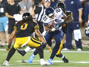 Argonauts' Vidal Hazelton (21) is brought down by Rico Murray (left) and Donald Washington (right) of the Tiger-Cats during CFL action at Tim Hortons Field in Hamilton, Ont., on Monday, Aug. 3, 2015. (Dave Abel/Toronto Sun)
