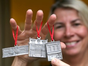 Jan MacDonald, projects manager-marketing with Downtown Kingston! shows off three of the five pewter ornaments on Thursday November 12 2015 available this year. From left,  are Robert Meek School, Hotel Belvedere,  and Cooke's Find Foods and Coffee Ian MacAlpine /The Kingston Whig-Standard/Postmedia Network