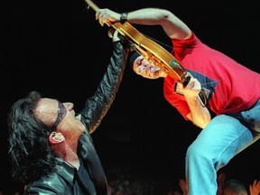 This file picture taken on July 17, 2001 shows U2's group members Bono (L) and "the Edge" (R) performing during a concert as part of their "Elevation Tour" in Paris. U2 was scheduled to perform in the renovated Bercy's Arena in Paris on Saturday, November 14, 2015, but the show has been cancelled after deadly attacks in Paris.  AFP PHOTO / BERTRAND GUAY