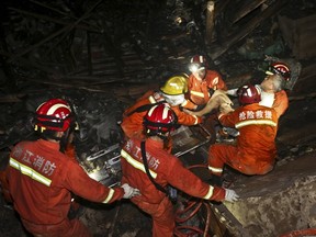 Rescuers pull out a man from the debris at the site of a landslide in Yaxi township of Lishui, Zhejiang province, China, November 14, 2015. A landslide occurred on Friday night in Lishui and buried over 20 houses underneath. Four people are confirmed dead and 33 others remained missing, local media reported. REUTERS/Stringer