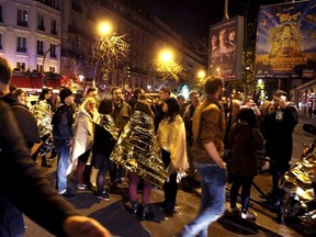 People warm up under protective thermal blankets as they gather on a street near the Bataclan concert hall following fatal attacks in Paris, Nov. 14, 2015. REUTERS/Philippe Wojazer