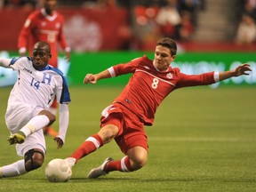 Oscar Boniek Garcia of Honduras and Will Johnson of Canada battle for the ball during their FIFA 2018 World Cup Russia Qualifier at BC Place in Vancouver on Nov. 13, 2015. (AFP PHOTO/Don MacKinnon)