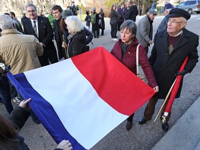 Marie-Christine Dauriac rolls up a French flag following a vigil showing solidarity with the victims in France at the Manitoba Legislature in Winnipeg on Sat., Nov. 14, 2015. (Kevin King/Winnipeg Sun/Postmedia Network)