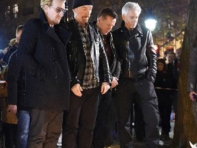 U2 lead singer Bono, guitarist The Edge, drummer Larry Mullen Jr and bass player Adam Clayton pay homage to attack victims near the Bataclan concert hall on Saturday, Nov. 14, 2015 in Paris, a day after a series of coordinated attacks in the French capital. (AFP)