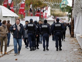 Police patrol as people walk past shuttered stalls at a largely deserted Christmas market in Paris on Nov.14, 2015 following a series of coordinated attacks in and around Paris late Friday. (AFP PHOTO / FRANCOIS GUILLOT)