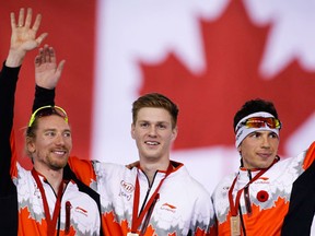 Canada's Ted-Jan Bloemen, left, and teammates Ben Donnelly, centre, and Jordan Belchos, celebrate their gold medal win on the podium following the men's team pursuit competition at the ISU World Cup speed skating event in Calgary, on Saturday, Nov. 14, 2015. (THE CANADIAN PRESS/Jeff McIntosh)