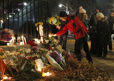 A man leaves a candle at the French embassy during a vigil in Ottawa on November 14, 2015, one day after the terrorist attacks in Paris. Stirring renditions of "La Marseillaise" rang out Saturday from Dublin to New York as global landmarks were bathed in the French colors and thousands marched in solidarity with Paris after attacks that left at least 129 dead. AFP Photo/Patrick Doyle