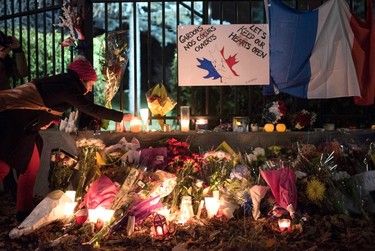 A woman lights candles after a vigil, outside the Embassy of France in Ottawa, following Friday's terrorist attacks in Paris, on Saturday, Nov. 14, 2015. THE CANADIAN PRESS/Justin Tang