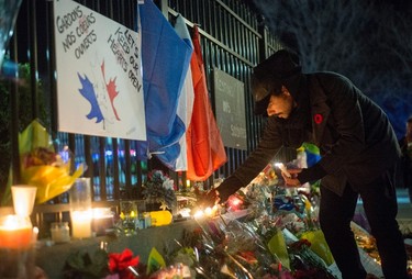 A man lights candles after a vigil outside the Embassy of France in Ottawa, following Friday's terrorist attacks in Paris, on Saturday, Nov. 14, 2015. THE CANADIAN PRESS/Justin Tang