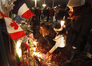 Women leave candles at the French embassy during a vigil in Ottawa on November 14, 2015, one day after the terrorist attacks in Paris. Stirring renditions of "La Marseillaise" rang out Saturday from Dublin to New York as global landmarks were bathed in the French colors and thousands marched in solidarity with Paris after attacks that left at least 129 dead. AFP Photo/Patrick Doyle