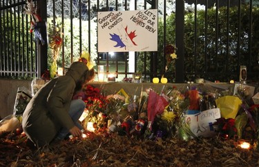 A woman lights a candle at the French embassy during a vigil in Ottawa on November 14, 2015, one day after the terrorist attacks in Paris. Stirring renditions of "La Marseillaise" rang out Saturday from Dublin to New York as global landmarks were bathed in the French colors and thousands marched in solidarity with Paris after attacks that left at least 129 dead. AFP Photo/Patrick Doyle
