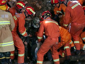 In this Saturday, Nov. 14, 2015 photo, rescuers remove a body found in the aftermath of a landslide in Lishui in east China's Zhejiang province. (Chinatopix Via AP)