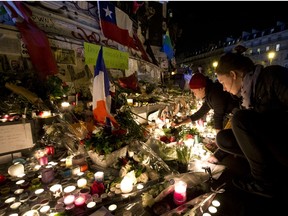People light candles at a makeshift memorial in tribute to the victims of Paris' attacks' on Nov. 15, 2015 at the place de la Republique in Paris. Islamic State jihadists claimed a series of coordinated attacks by gunmen and suicide bombers in Paris on Nov. 13 that killed at least 129 people in scenes of carnage at a concert hall, restaurants and the national stadium. (AFP PHOTO/JOEL SAGET)