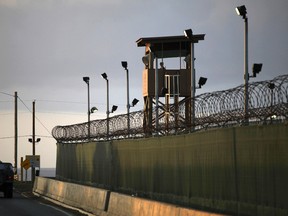 In this March 30, 2010, file photo, reviewed by the U.S. military, a U.S. trooper stands in the turret of a vehicle with a machine gun, left, as a guard looks out from a tower at the detention facility of Guantanamo Bay U.S. Naval Base in Cuba.   (AP Photo/Brennan Linsley, File)