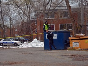 A pair of police officers open the lid of a nearby dumpster in the parking lot across the street from the scene of a fatal shooting in Vanier on Nov. 15, 2015.
SAM COOLEY / OTTAWA SUN /POSTMEDIA NETWORK