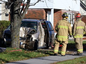 Ottawa firefighters survey the scene where a woman driving a minivan struck a tree along westbound Smyth Rd. near Haig Dr. on Monday, Nov. 16, 2015. She was pronounced dead at hospital. (Errol McGihon/Ottawa Sun/Postmedia Network)