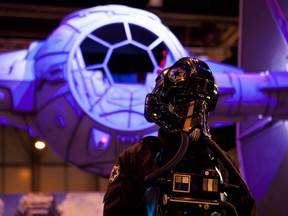 An actor dressed as a TIE figther pilot poses by a giant model of a Star Wars' TIE fighter for the presentation of US game developer, publisher and distributor Electronic Arts (EA)'s "Star Wars Battlefront", during the Madrid Games Week 2015 in Madrid on October 1, 2015. The video game fair is open from October 1 to 4.  AFP PHOTO/ SEBASTIEN BERDA