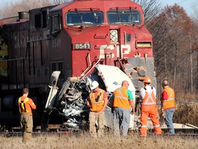 Volunteer firefighters and employees of Canadian Pacific Railway are pictured at the scene of a crash involving a CP freight train and a dump-box style truck that claimed the life of an unidentified male victim. in near Bothwell, Ont. on Monday November 16, 2015. (Ellwood Shreve, The Daily News)