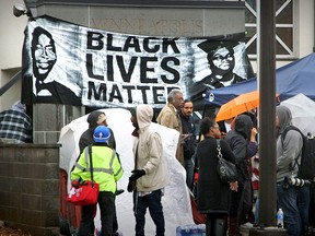 In this image from video, community members and activists gather outside outside a police precinct Monday, Nov. 16, 2015, in Minneapolis. Activists are demanding that Minneapolis police identify an officer who shot a black man suspected in an assault on Sunday. Witnesses say the man was handcuffed when he was shot, sparking protests and an overnight encampment at the police department. (Matt Gillmer/Star Tribune via AP)