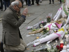 A man pays his respects at a pop-up memorial to the victims of an attack along a rail cordon close to the Bataclan theatre in the 11th district of Paris. (AFP PHOTO)