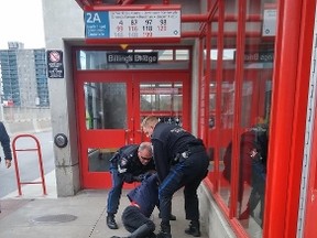 Two OC Transpo special constables restrain a woman at the Billings Bridge transit station in the late morning of Saturday, Nov. 14, 2015.
Photo by Trevor Crew.