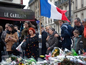 People gather in front of Le Carillon cafe, a site of the recent attacks, in Paris, Monday. AP Photo/Jerome Delay