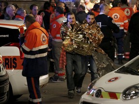 People warm up under protective thermal blankets as they walk on a street near the Bataclan concert hall following fatal attacks in Paris, France, November 14, 2015. A Foreign Affairs spokeswoman has confirmed that a Canadian was among those injured during the attacks. REUTERS/Benoit Tessier