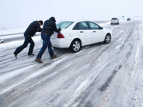 Curtis Hansen, left, and Jeff Malley push a motorist up the icy northbound off-ramp from I-25 to Baptist Road Wednesday, Nov. 11, 2015, north of Colorado Springs, Colo. The storm system that dropped a foot of snow in the Rockies was making travel hazardous as it headed east on Wednesday, menacing the Plains with heavy snow and threatening turbulent weather, even tornadoes, in parts of the Midwest.  (Mark Reis/The Gazette via AP)